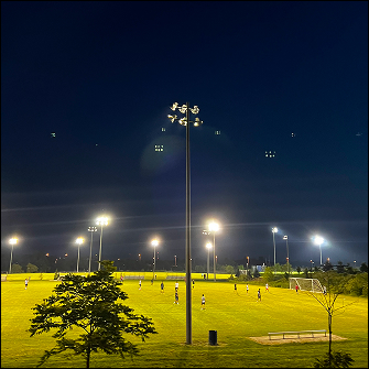 photo of people playing soccer on a field at night